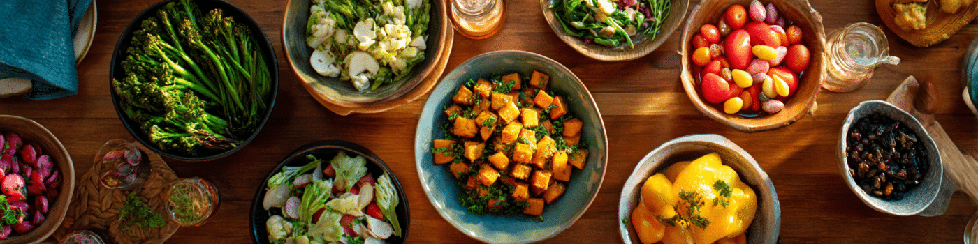 A warm, inviting kitchen scene featuring a beautifully arranged meal preparation for someone with ALS. The image shows a wooden table with several colorful, nutrient-dense dishes of varying textures